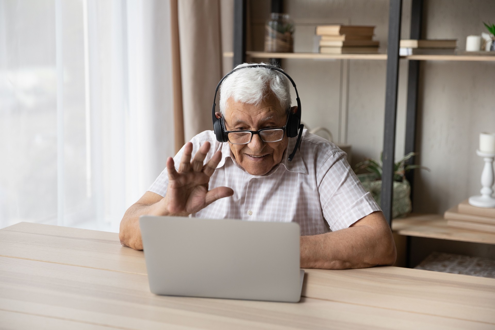 Older man wear headset start videoconference seated at table